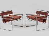 a pair of brown leather chairs with chrome frame legs