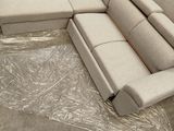 a couch that is sitting on a plastic sheet in the middle of a room
