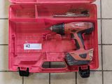 une boîte à outils rose contenant des outils, posée sur un sol carrelé