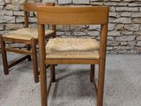 two wooden chairs sitting next to each other in front of a stone wall