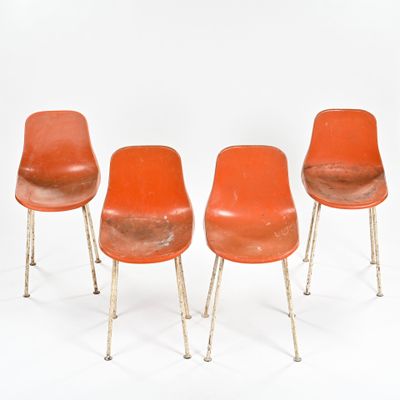 trois chaises orange placées les unes à côté des autres sur une surface blanche