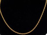 a gold chain necklace on a black mannequin display