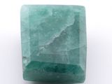un gros plan d'une pierre verte sur une surface blanche