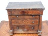une petite commode en bois posée sur un parquet