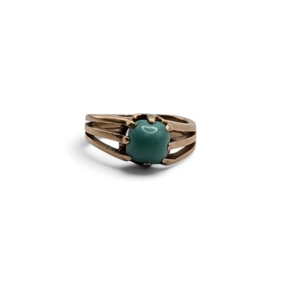 Gros plan sur une bague ornée d'une pierre verte