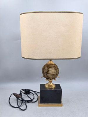 une lampe dorée avec un pied noir et un abat-jour beige