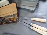 four forks and a knife in a case on a table