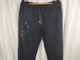 Le pantalon Nike est suspendu à un cintre devant un rideau blanc.