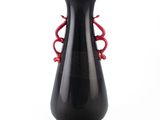 un vase noir avec une anse rouge sur fond blanc