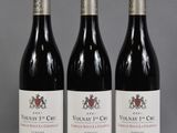 trois bouteilles de vin rouge posées sur une table l'une à côté de l'autre