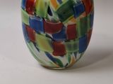 un vase en verre multicolore posé sur une surface blanche