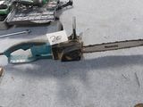 une tronçonneuse posée par terre à côté d'autres outils