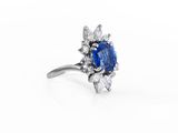 a close up of a blue sapphire and diamond ring on a white background