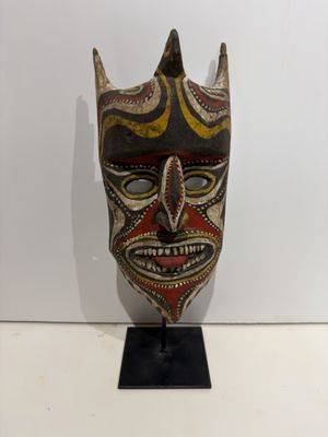 a close up of a mask on a stand on a white surface