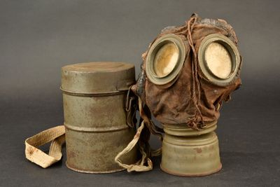 a gas mask sitting next to a canister on a table