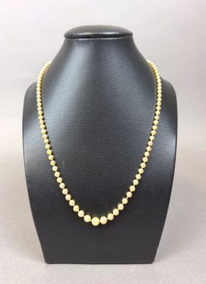 a yellow beaded necklace on a black mannequin