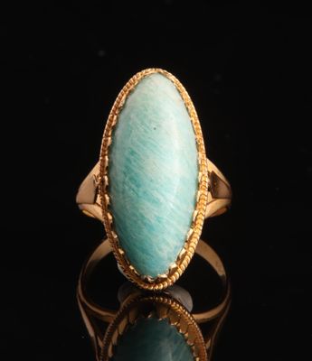 gros plan d'une bague en or avec une pierre verte