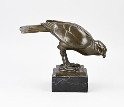 sculpture en bronze représentant un oiseau sur un socle en marbre, sur fond blanc