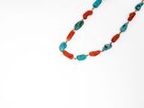 Collier de perles turquoise et corail sur fond blanc
