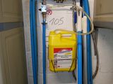 un tuyau bleu fixé au mur, auquel est raccordé un récipient jaune