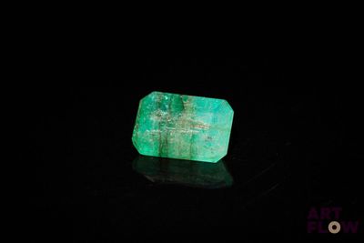a close up of a green emerald stone on a black surface