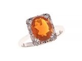 un gros plan d'une bague ornée d'une pierre orange entourée de diamants