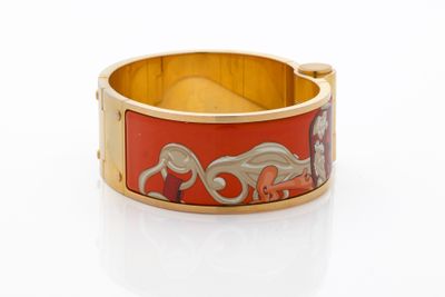 une image représentant un bracelet rouge et doré orné de chevaux