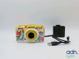 un appareil photo numérique et un chargeur posés sur une surface blanche