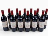 six bottles of red wine lined up in a row on a white surface