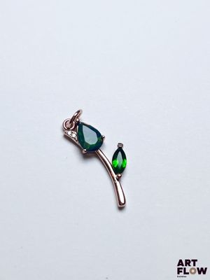un gros plan d'un pendentif vert et argenté posé sur une surface blanche
