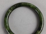 a close up of a green bracelet on a white surface