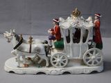 a figurine of a horse drawn carriage with people on it