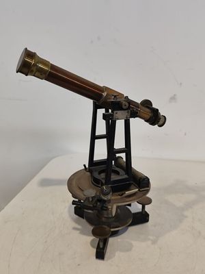 un télescope ancien en laiton posé sur un socle, sur une surface blanche
