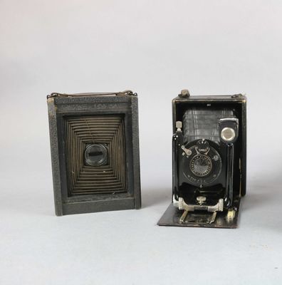 two old cameras sitting next to each other on a white surface