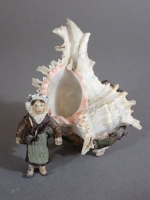 a figurine of a woman standing next to a shell