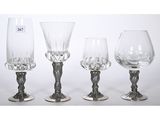 three glass goblets and a wine glass sitting on a table