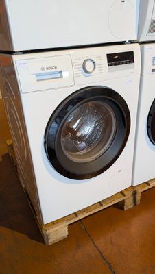 two washers and a dryer stacked on pallets