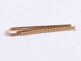 a gold colored hair clip on a white surface