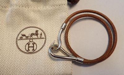 un petit sac muni d'une bandoulière en cuir marron et d'un fermoir argenté