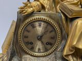 a statue of a man holding a book and a clock