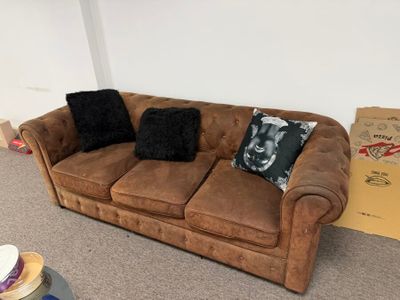a brown couch in a living room with a box on the floor