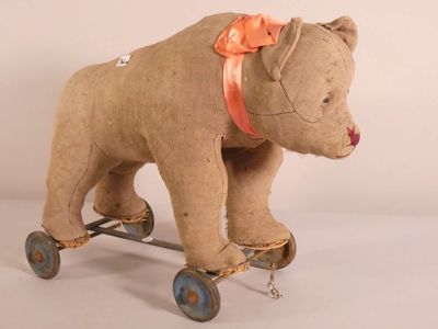 un ours en peluche sur un skateboard, avec un nœud sur la tête