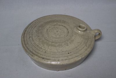 a white bowl with a handle on a white table
