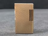 a gold lighter sitting on top of a table next to a black wall