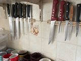 many bowls and knives hanging on the wall in the kitchen