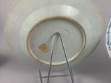 a white and blue bowl and a blue and white bowl on a stand