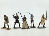 several figurines of star wars characters are posed on a white surface