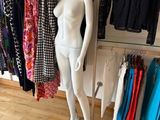 a mannequin in front of a rack of clothes