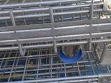 une cage métallique posée par terre, avec un oiseau à l'intérieur
