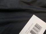 a white label on a black shirt on a bed